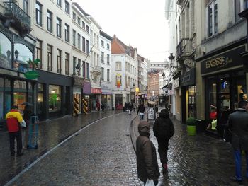 Rear view of people walking on wet street in rainy season