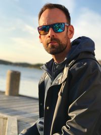 Portrait of man wearing sunglasses standing against sea