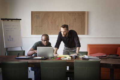 Businessmen looking at laptop computer while meeting in office