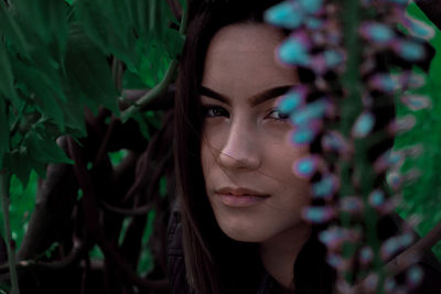 Close-up portrait of young woman by plants