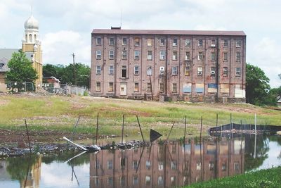 Canal by buildings against sky