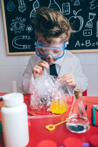 Boy doing scientific experiment on table in classroom