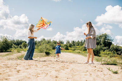 A mother flies a kite with her daughters during a family vacation in the country