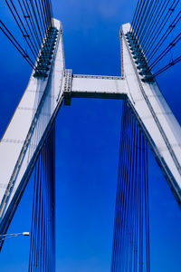 Low angle view of suspension bridge against blue sky