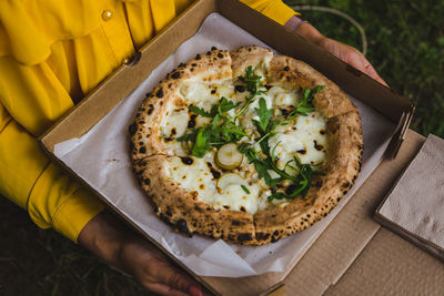 High angle view of hand holding pizza