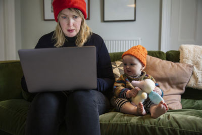 Young woman using laptop while sitting on sofa at home