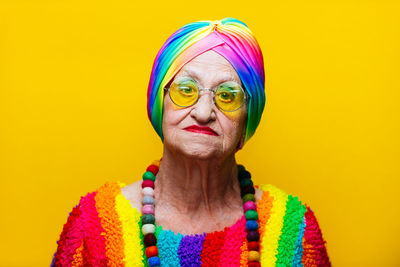 Portrait of woman wearing colorful clothing against yellow background