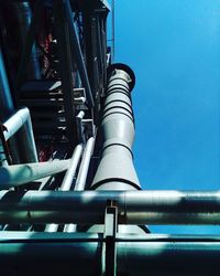 Low angle view of pipes against blue sky