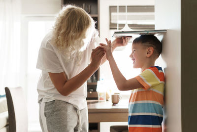 Mother measuring sons height at home