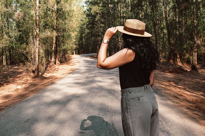  woman standing on the road in a pine forest