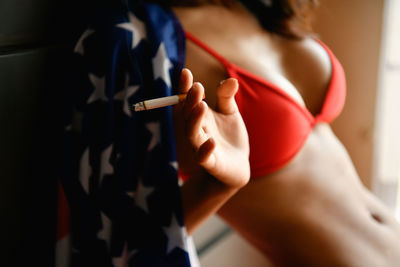 Midsection of sensuous woman holding cigarette