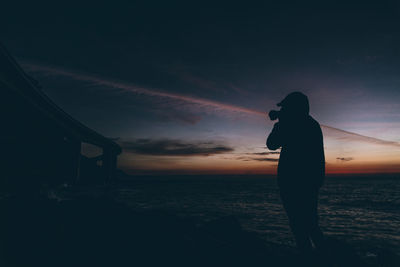 Silhouette of people standing on beach at sunset