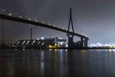 Illuminated bridge over river in city at night