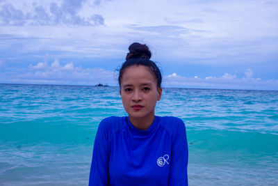 Portrait of young woman swimming in sea against sky