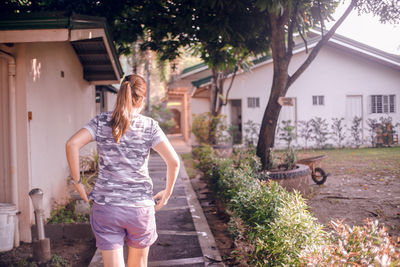 Rear view of woman walking by house