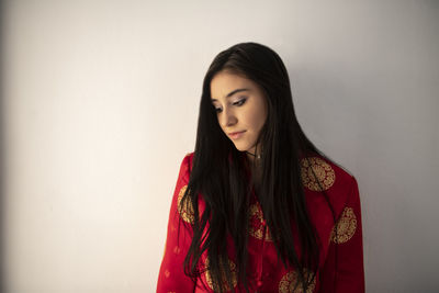 Beautiful young woman standing against wall