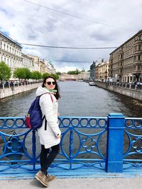 Portrait of woman standing on railing against river