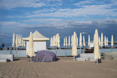 Closed parasol at beach against sky