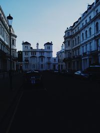 Cars on street in city against clear sky