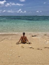 Full length of shirtless man on beach against sky