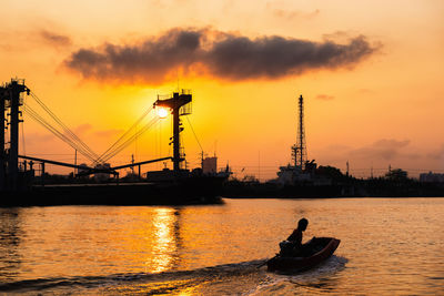 Silhouette man on boat in sea against sky during sunset