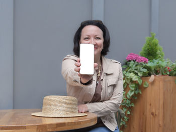 Portrait of smiling young woman holding smart phone on table