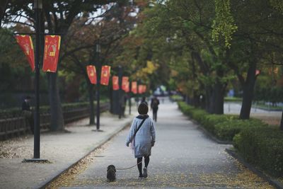 Woman walking dog on footpath