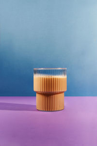 Glass of coffee with milk on color block background