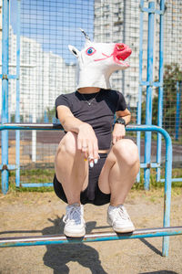  woman wear unicorn head sitting on playground