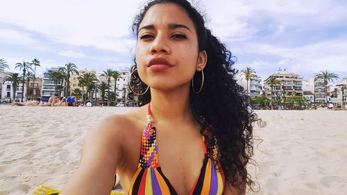 Close-up of woman with wavy black hair at beach against sky