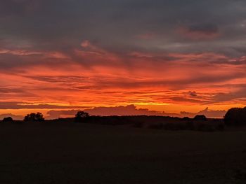 Scenic view of dramatic sky over silhouette landscape during sunset