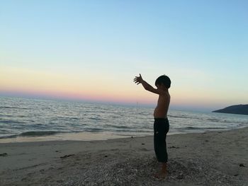 Full length of man on beach against sky during sunset