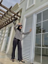 Full length of woman in hijab standing by building window