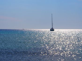 Sailboat sailing in sea against clear sky