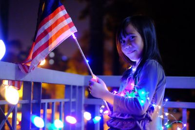 Close-up of girl holding illuminated lighting equipment at night