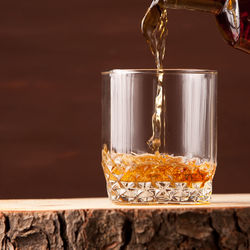 Whiskey glass on wooden table, brown background