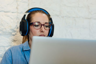 Woman working with her laptop and is focused on listening with her headphones