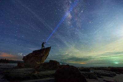 Person white lightbeam on rock at beach