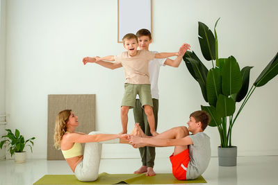 Sports family, a woman, a boy and two teenagers perform group yoga exercises on a sports mat.