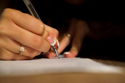Cropped image of woman writing on paper