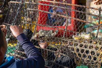 Man in cage seen through chainlink fence