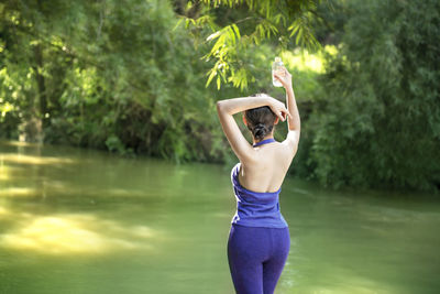 Woman standing on lake against trees
