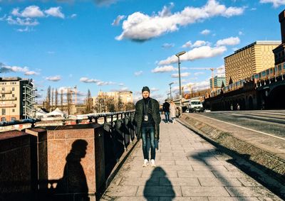 Man standing on bridge in city against sky