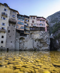 Buildings by river in city against clear sky