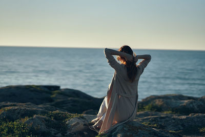 Woman with umbrella at sea shore against sky