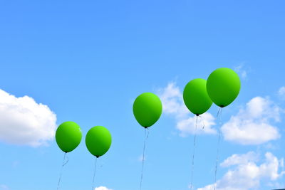 Low angle view of balloons flying against blue sky