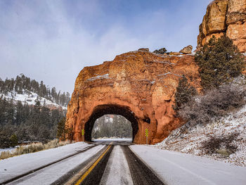 Road leading towards rock formation against sky