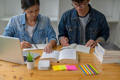 Man and woman using mobile phone while sitting on table