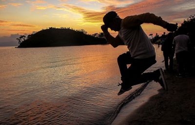 Silhouette men on beach against sky during sunset