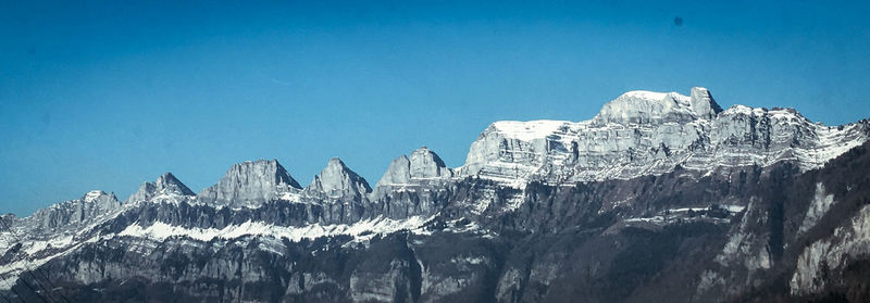 Panoramic view of snowcapped mountains against blue sky